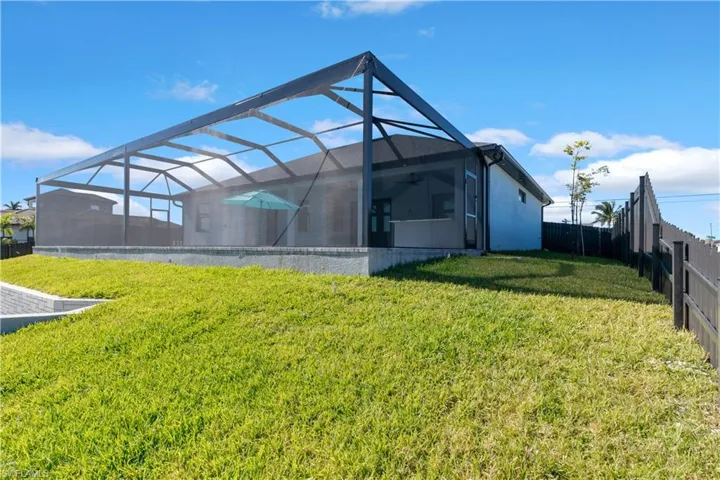Back of property featuring a lanai and a yard