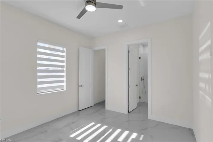 Unfurnished bedroom featuring connected bathroom, multiple windows, and ceiling fan
