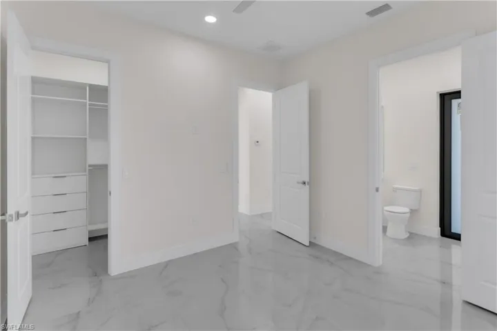 Unfurnished bedroom with ensuite bathroom, a spacious closet, and a closet