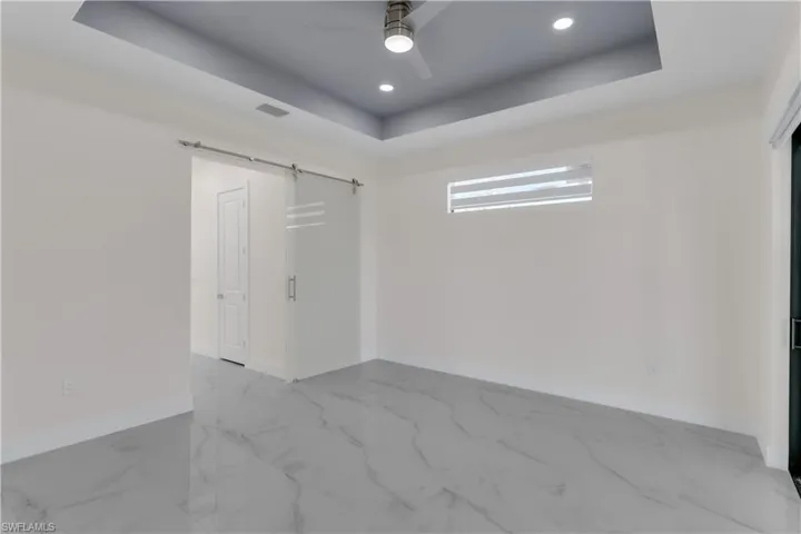 Unfurnished room with ceiling fan and a tray ceiling