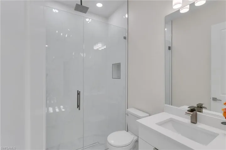 Bathroom with an enclosed shower, vanity, and toilet
