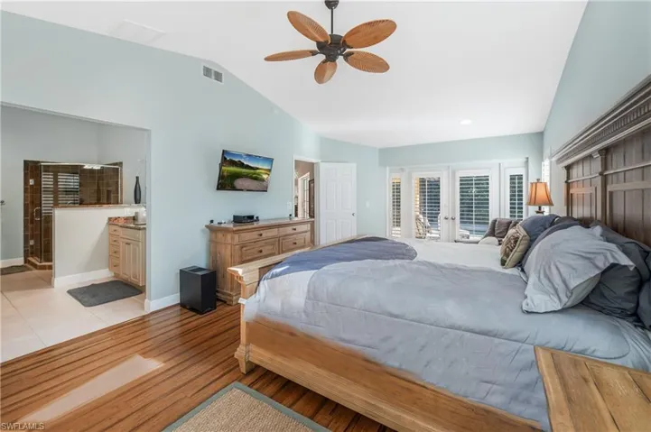 Bedroom featuring lofted ceiling, ensuite bath, access to exterior, light hardwood / wood-style floors, and french doors