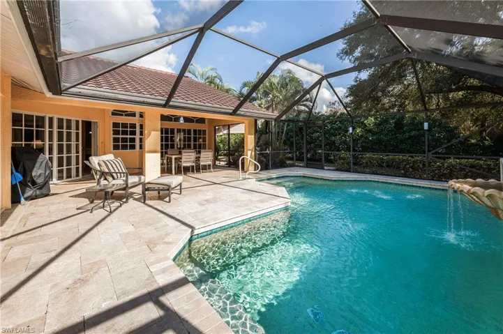 View of pool featuring grilling area, a patio, and glass enclosure