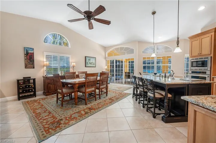 Tiled dining area with sink, high vaulted ceiling, and ceiling fan