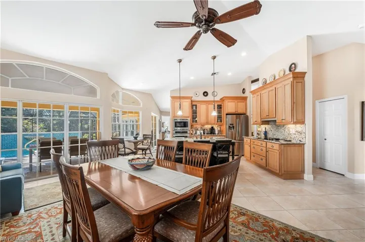 Tiled dining room with ceiling fan and vaulted ceiling