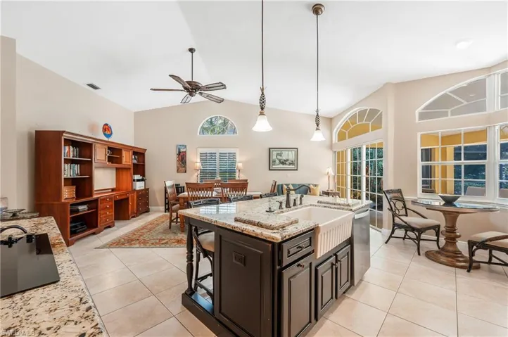 Kitchen featuring light stone counters, decorative light fixtures, stainless steel dishwasher, and light tile patterned flooring