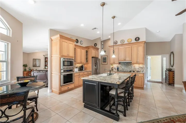 Kitchen featuring pendant lighting, sink, a kitchen island with sink, stainless steel appliances, and light stone countertops