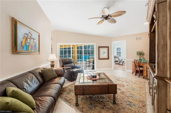 Living room with light tile patterned floors, vaulted ceiling, and ceiling fan