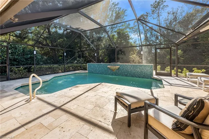 View of pool with pool water feature, a patio, and glass enclosure