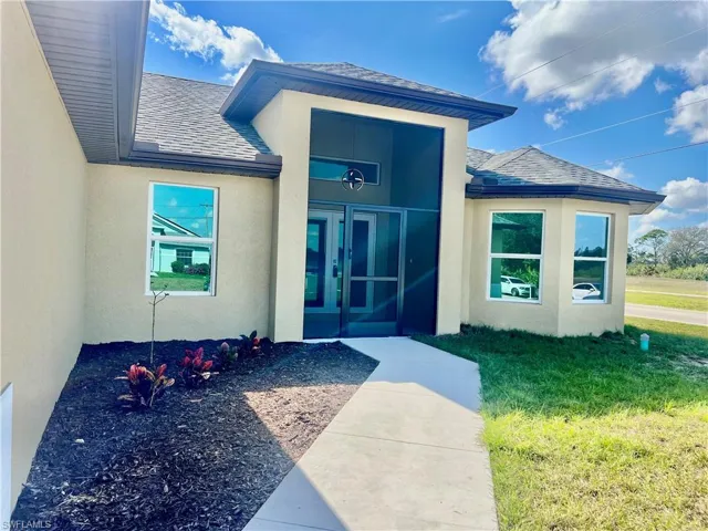 View of exterior entry with a lawn and screened front entryway.
