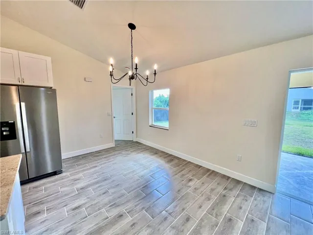Dining room with a chandelier, vaulted ceiling.
