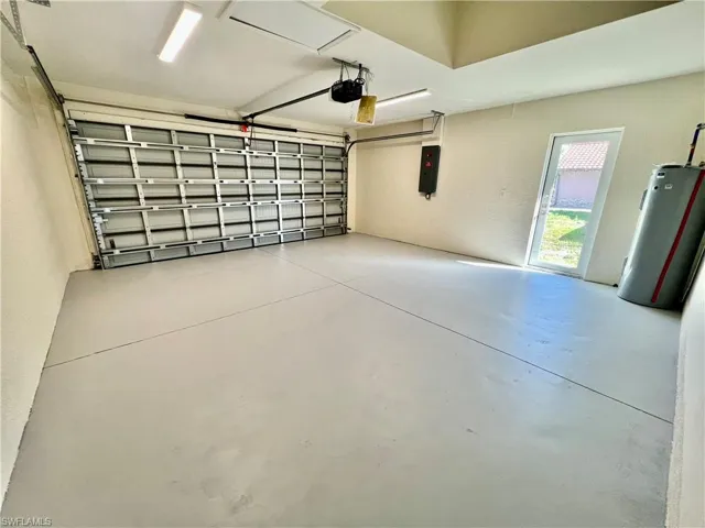 Garage with a garage door opener, electric panel, water heater and seal coated floors.
