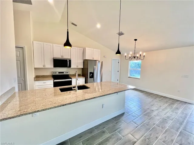 Kitchen featuring sink, white cabinetry, GRANITE COUNTERTOPS WITH BREAKFAST BAR,  a chandelier, and stainless steel appliances
