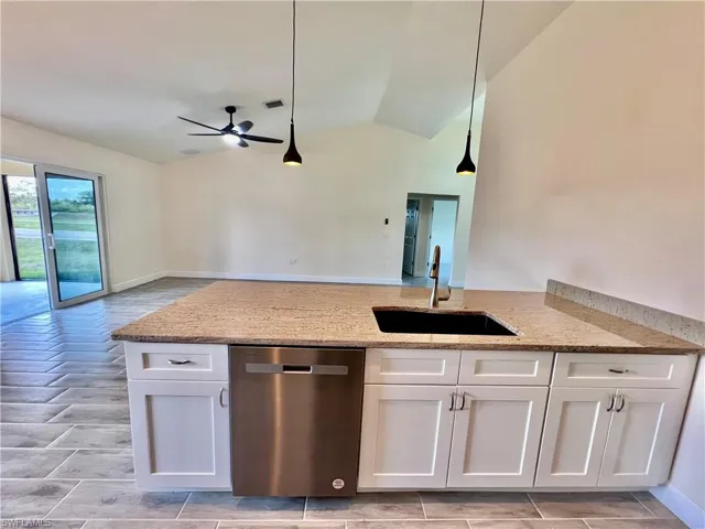 Kitchen featuring sink, white cabinetry, GRANITE COUNTERTOPS WITH BREAKFAST BAR,  a chandelier, and stainless steel appliances