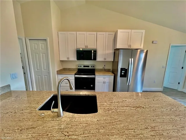 Kitchen featuring sink, white cabinetry, GRANITE COUNTERTOPS WITH BREAKFAST BAR,  a chandelier, and stainless steel appliances