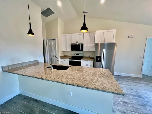 Kitchen featuring sink, white cabinetry, GRANITE COUNTERTOPS WITH BREAKFAST BAR,  a chandelier, and stainless steel appliances