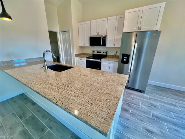 Kitchen featuring sink, white cabinetry, GRANITE COUNTERTOPS WITH BREAKFAST BAR,  a chandelier, and stainless steel appliances