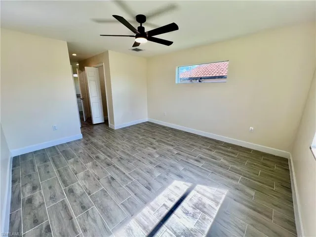Primary bedroom featuring wood plank porcelain tile floors leading to ensuite bathroom and dual walk in closets.