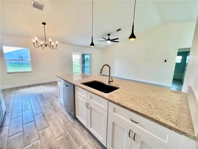 Kitchen featuring sink, white cabinetry, GRANITE COUNTERTOPS WITH BREAKFAST BAR,  a chandelier, and stainless steel appliances
