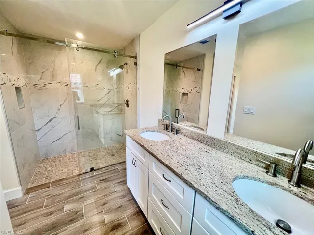 Primary bathroom with dual sinks, granite tops and frameless glass shower door.