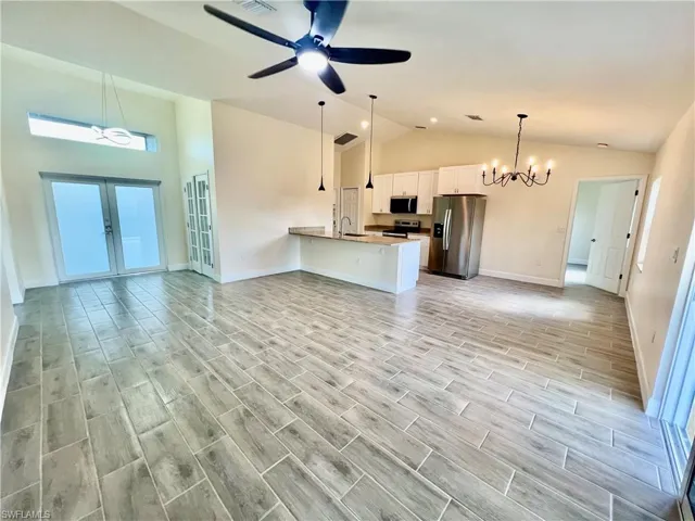 Living room featuring French doors, high cathedral ceiling, sink, and ceiling fan with notable chandelier