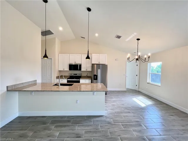 Kitchen featuring sink, white cabinetry, GRANITE COUNTERTOPS WITH BREAKFAST BAR,  a chandelier, and stainless steel appliances