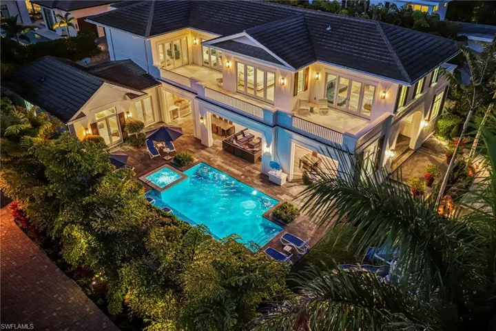 Rear view of property featuring a patio area, a pool with connected hot tub, stucco siding, and outdoor dining area