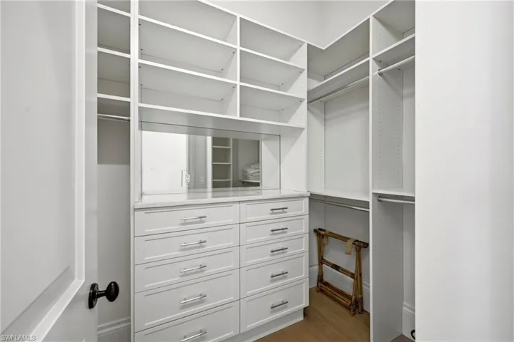 Walk in closet with dark wood finished floors
