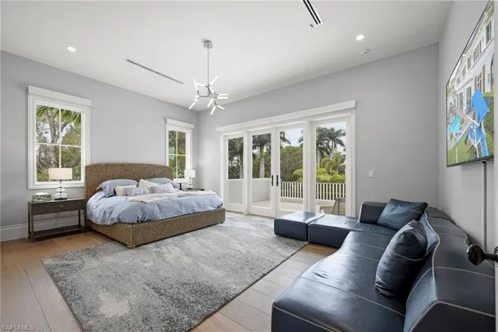 Bedroom featuring light wood-type flooring, access to exterior, and suspended lighting