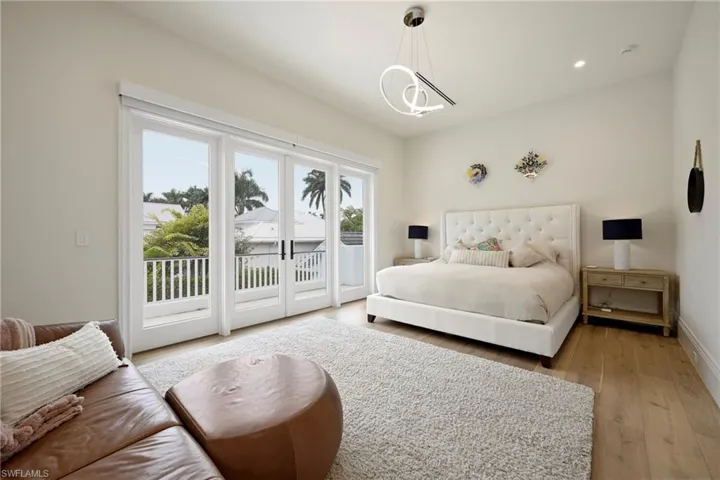 Bedroom with light wood-type flooring, access to outside, french doors, and hanging lights
