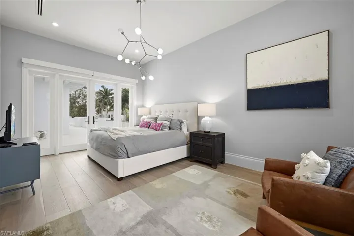 Bedroom with light wood-type flooring, french doors, access to outside, hanging lights, and lofted ceiling