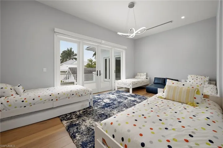 Bedroom featuring light wood finished floors, access to outside, hanging lights, and french doors