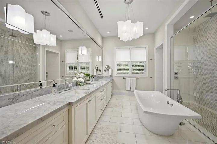 Full bathroom with a shower stall, double vanity, light tile patterned flooring, a freestanding tub, and suspended lighting