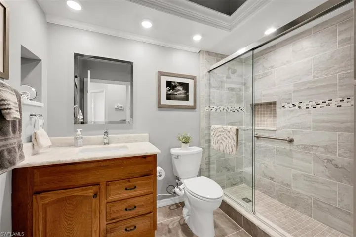 Bathroom featuring tile patterned flooring, toilet, walk in shower, vanity, and crown molding