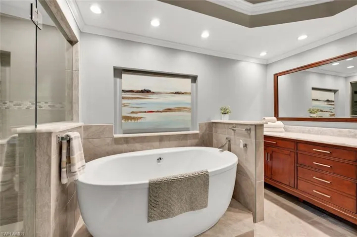 Bathroom featuring a washtub, vanity, tile walls, and ornamental molding