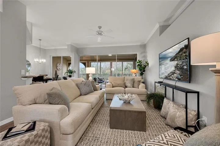 Living room with light hardwood / wood-style floors, ornamental molding, and ceiling fan with notable chandelier