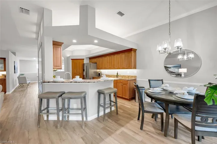 Kitchen with light stone counters, a chandelier, decorative light fixtures, high end fridge, and ornamental molding