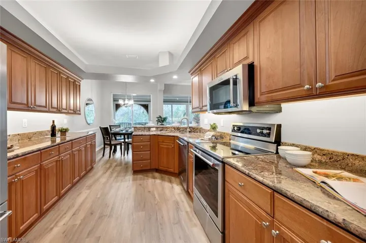 Kitchen featuring light stone countertops, a chandelier, stainless steel appliances, light hardwood / wood-style floors, and sink
