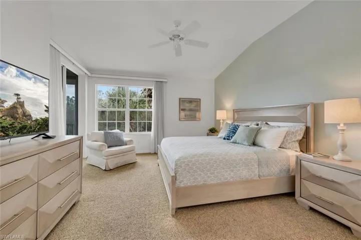 Bedroom featuring ceiling fan, vaulted ceiling, and light carpet
