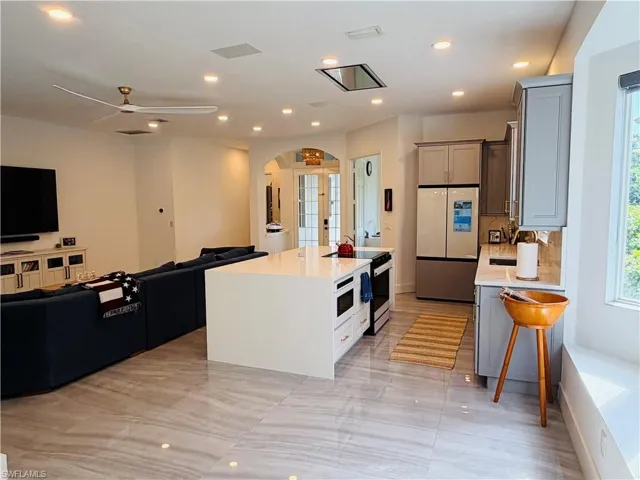 This open-concept living area features large format tile flooring, recessed lighting, and a contemporary ceiling fan