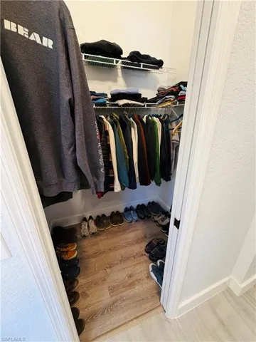 This closet features wire shelving, a clothing rod for hanging garments, and wood-look flooring