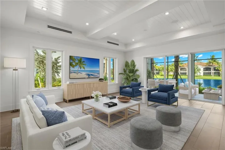 Living room featuring a tray ceiling, a water view, and light hardwood / wood-style flooring