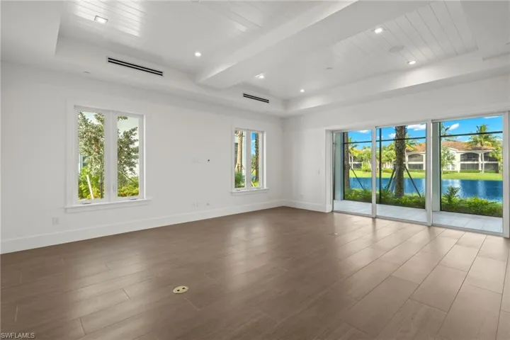 Unfurnished living room featuring a raised ceiling, hardwood / wood-style floors, a water view, and beam ceiling