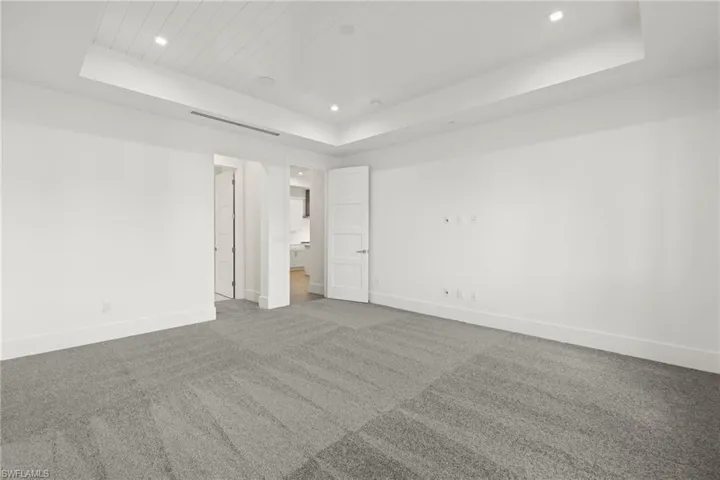Unfurnished view of bedroom with carpet flooring, connected full bathroom, and a raised ceiling