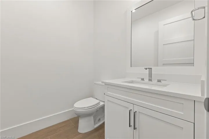 Bathroom with quartz vanity, toilet, and porcelain tile flooring