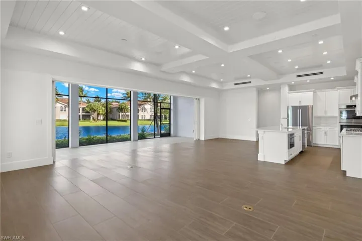 Unfurnished living room with beam ceiling, coffered ceiling, dark wood-type flooring, and a water view