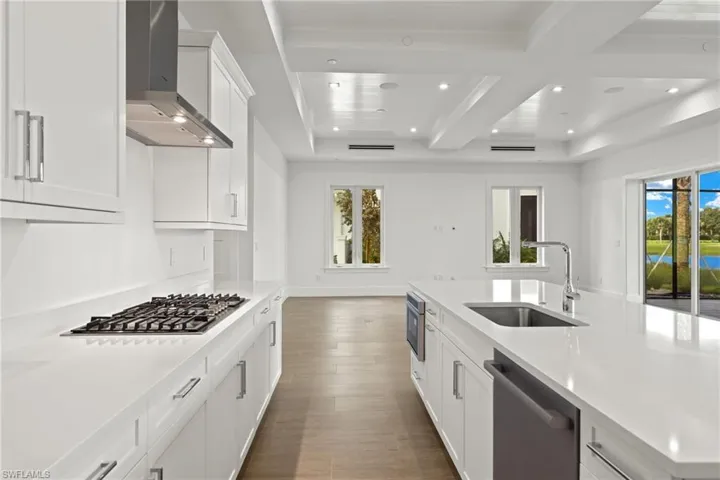 Kitchen featuring porcelain tile flooring, wall chimney exhaust hood, white cabinets, sink, and Bosch appliances with stainless steel finishes