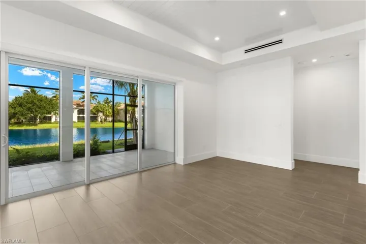 Unfurnished view of great/living room with a water view and a raised ceiling