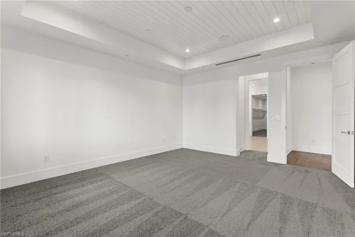 View of unfurnished MBR suite  with a raised ceiling and carpet