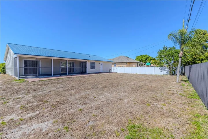Back of property featuring a fenced backyard, a sunroom, and a metal roof